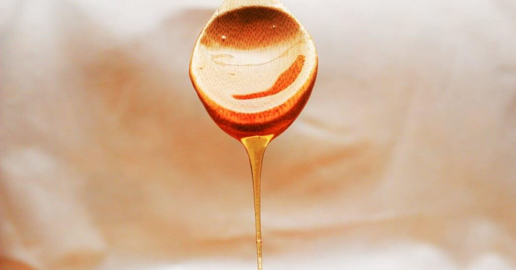 une cuillère pleine de miel posée sur une table