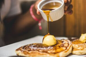 person pouring syrup into pancake